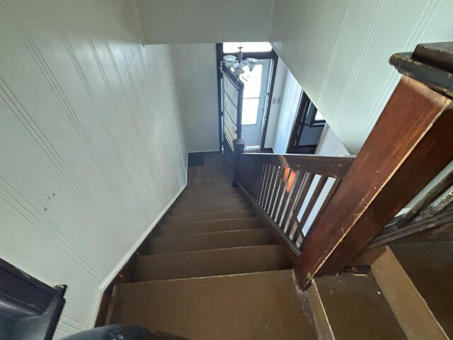 staircase featuring wood-type flooring and a notable chandelier