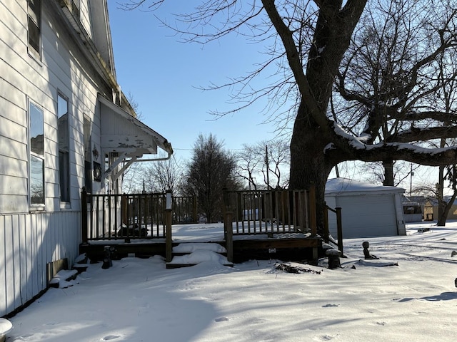 snowy yard featuring an outdoor structure and a wooden deck