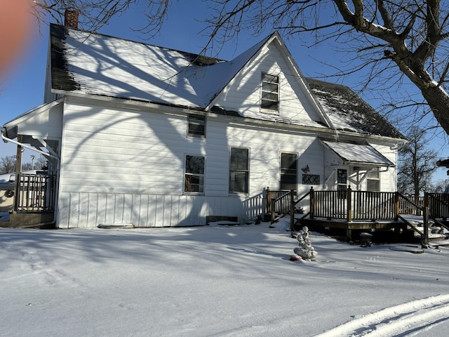 view of snowy exterior with a chimney and a deck