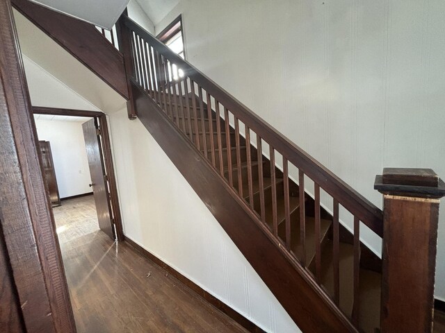 staircase featuring wood finished floors and a towering ceiling