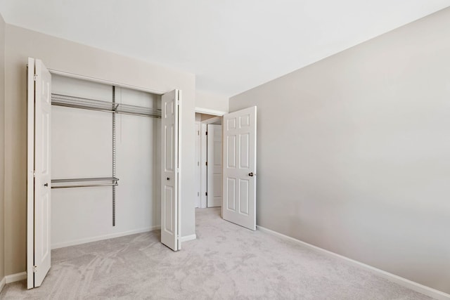 unfurnished bedroom featuring light carpet and a closet