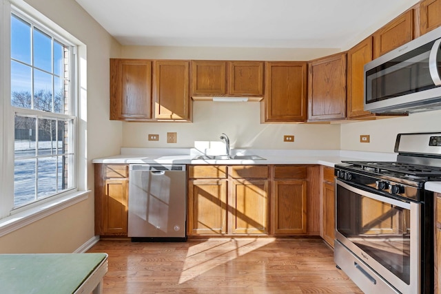 kitchen featuring a healthy amount of sunlight, stainless steel appliances, sink, and light wood-type flooring