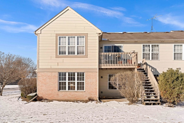 snow covered back of property featuring a balcony