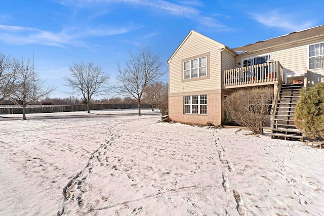 snow covered house featuring a wooden deck