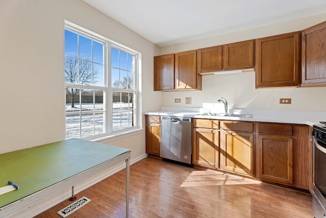 kitchen with sink, stainless steel dishwasher, and light wood-type flooring