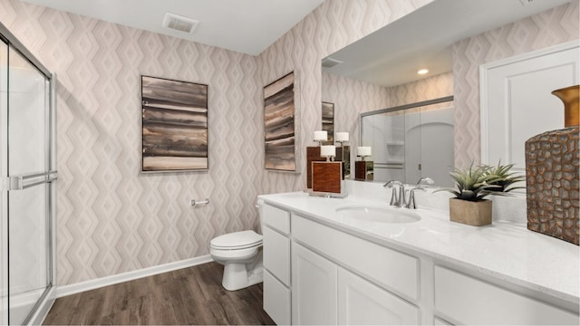 bathroom with a shower with door, vanity, wood-type flooring, and toilet