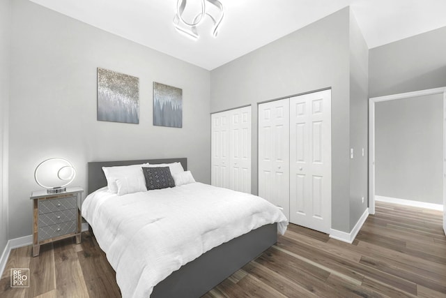 bedroom with two closets and dark hardwood / wood-style floors