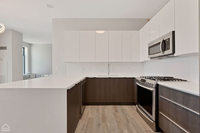 kitchen with appliances with stainless steel finishes, sink, white cabinets, and dark brown cabinetry