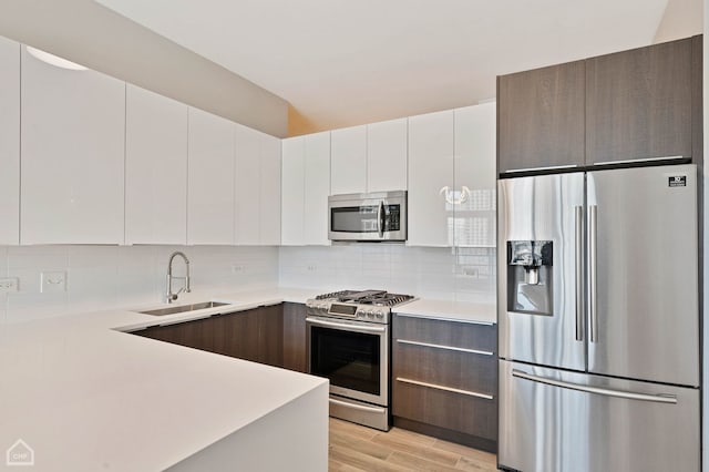 kitchen featuring sink, white cabinetry, dark brown cabinets, stainless steel appliances, and decorative backsplash