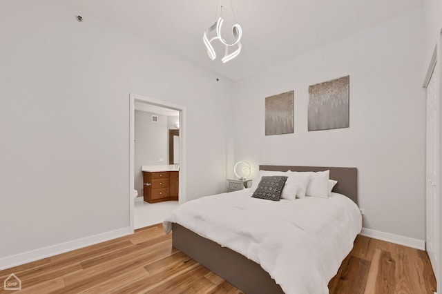 bedroom featuring light wood-type flooring and ensuite bath