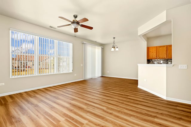 unfurnished living room with ceiling fan with notable chandelier and light wood-type flooring