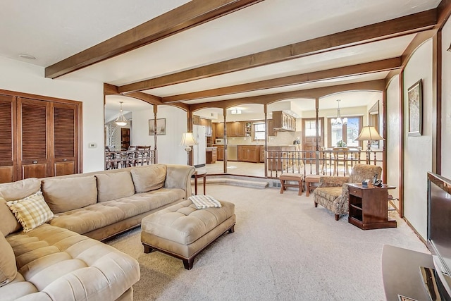 carpeted living room featuring beamed ceiling and a notable chandelier