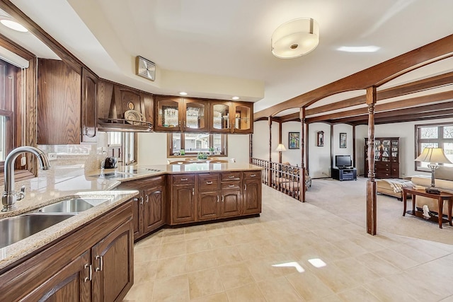 kitchen with premium range hood, sink, light stone counters, black electric stovetop, and beam ceiling