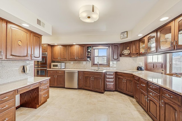 kitchen featuring stainless steel appliances, light stone countertops, sink, and backsplash