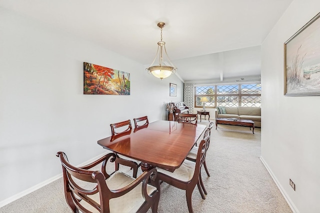 carpeted dining area featuring vaulted ceiling