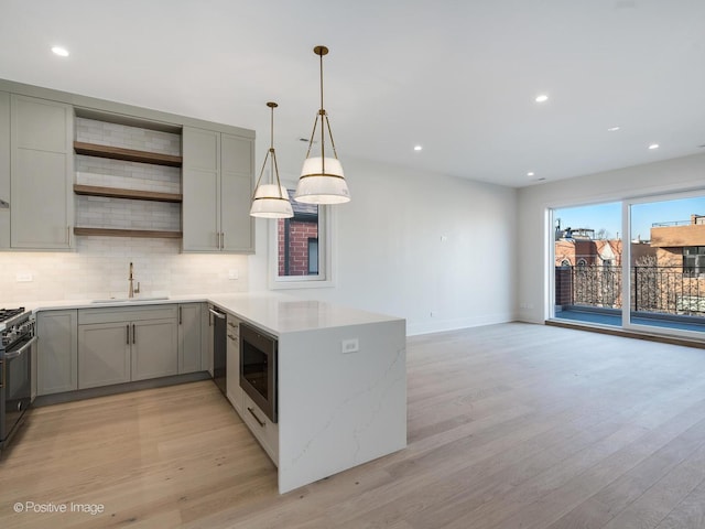 kitchen featuring sink, kitchen peninsula, light hardwood / wood-style flooring, pendant lighting, and stainless steel appliances