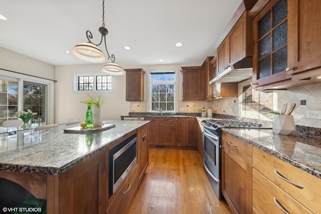 kitchen with backsplash, decorative light fixtures, stainless steel appliances, and a center island