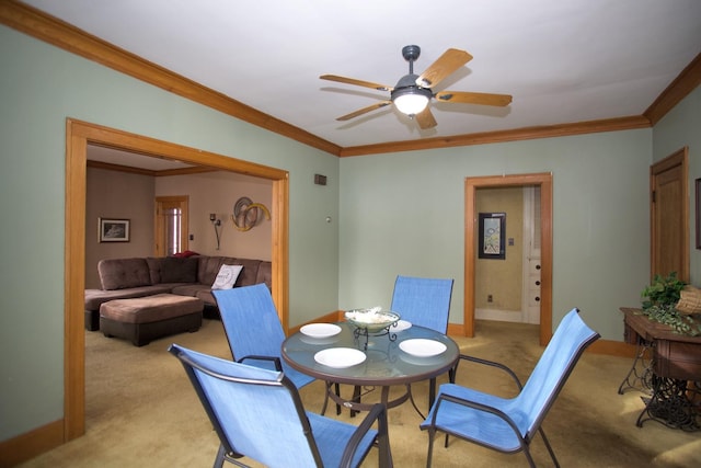 carpeted dining space featuring ornamental molding and ceiling fan