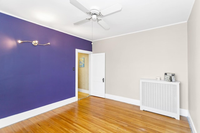 spare room with hardwood / wood-style flooring, ceiling fan, radiator heating unit, and ornamental molding