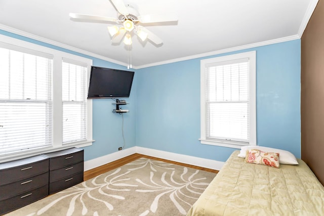 bedroom with multiple windows, wood-type flooring, crown molding, and ceiling fan