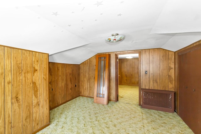 additional living space featuring light carpet, wooden walls, and vaulted ceiling