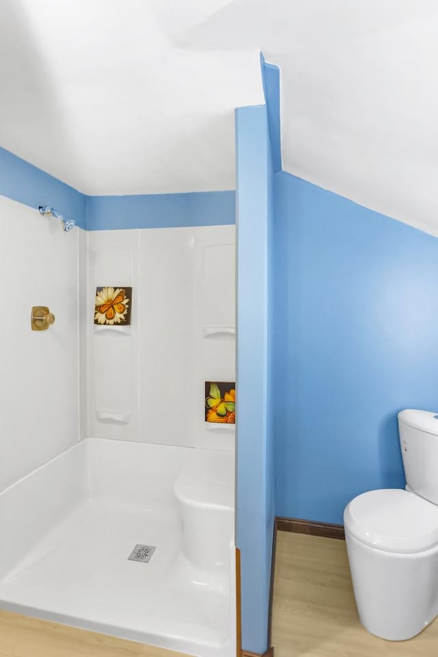 bathroom with wood-type flooring, toilet, and a shower