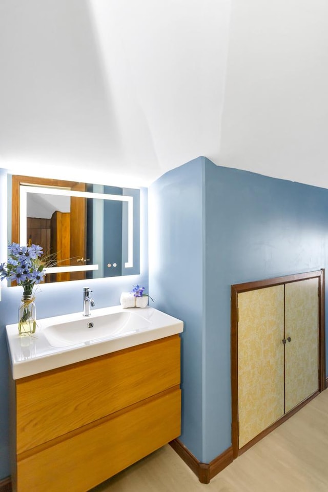 bathroom featuring vanity, lofted ceiling, and hardwood / wood-style floors