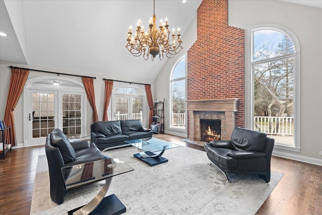 living room featuring french doors, high vaulted ceiling, hardwood / wood-style floors, and a notable chandelier