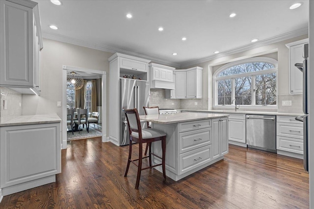 kitchen featuring a kitchen bar, white cabinetry, a center island, dark hardwood / wood-style floors, and stainless steel appliances