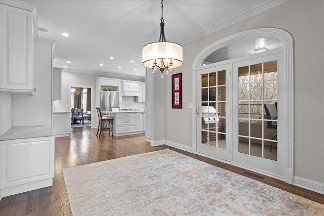 unfurnished dining area with crown molding, dark hardwood / wood-style floors, and an inviting chandelier