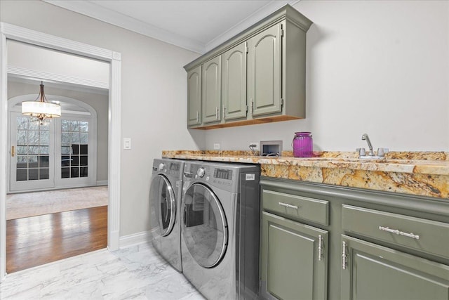 washroom with cabinets, ornamental molding, washer and dryer, and an inviting chandelier