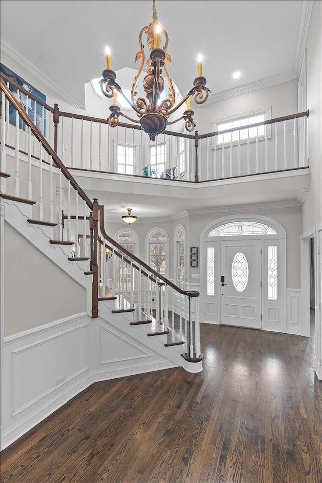 entrance foyer with a high ceiling, ornamental molding, dark hardwood / wood-style flooring, and a chandelier