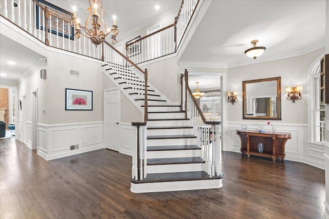 stairway with hardwood / wood-style floors, crown molding, and a chandelier