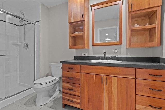 bathroom with tile patterned flooring, vanity, a shower with shower door, and toilet