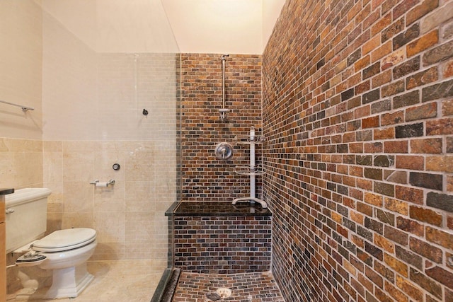 bathroom with a tile shower, tile walls, and toilet