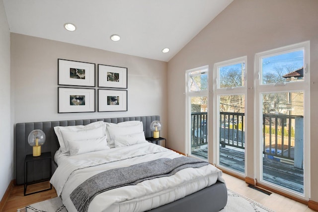 bedroom with multiple windows, vaulted ceiling, access to outside, and light wood-type flooring