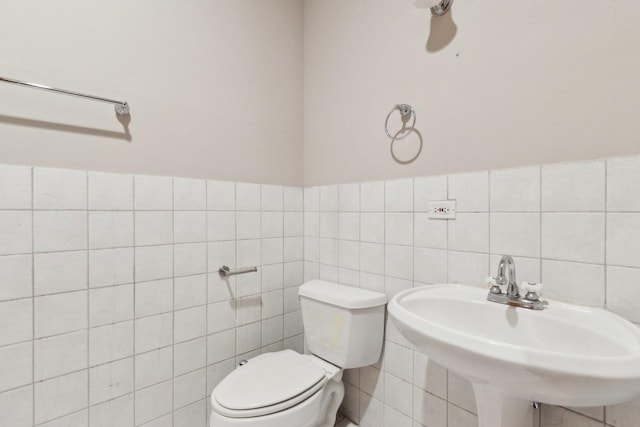 bathroom featuring toilet, sink, and tile walls