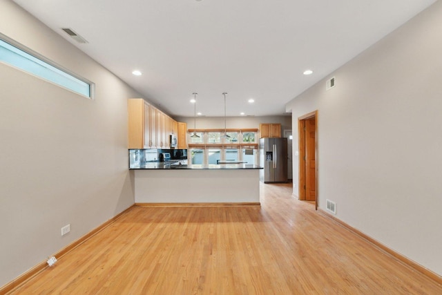 kitchen featuring pendant lighting, light hardwood / wood-style flooring, appliances with stainless steel finishes, light brown cabinetry, and kitchen peninsula