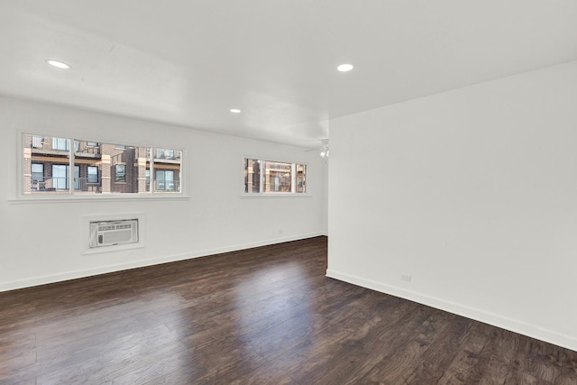 empty room with a wall mounted air conditioner, ceiling fan, and dark hardwood / wood-style floors