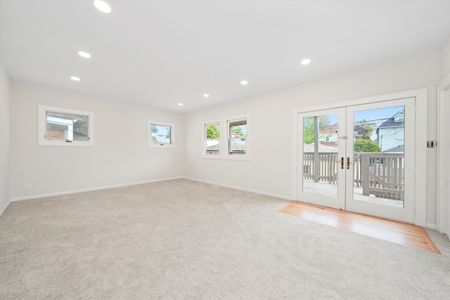 empty room with light colored carpet, recessed lighting, french doors, and baseboards