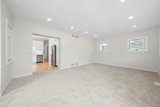 empty room with light colored carpet, recessed lighting, and baseboards