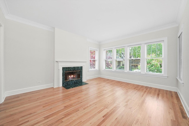 unfurnished living room featuring a fireplace, wood finished floors, baseboards, and ornamental molding