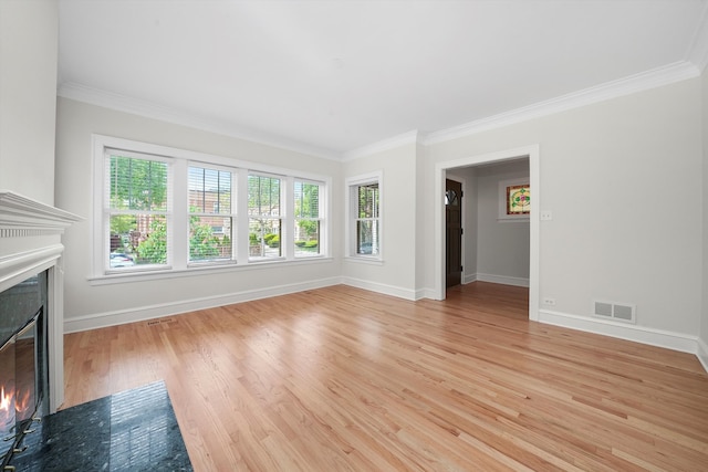 unfurnished living room with a fireplace with flush hearth, crown molding, baseboards, and light wood-style floors