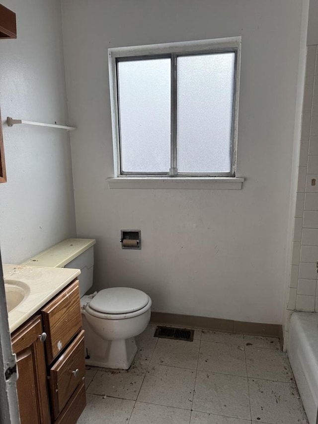 bathroom featuring vanity, a tub to relax in, and toilet