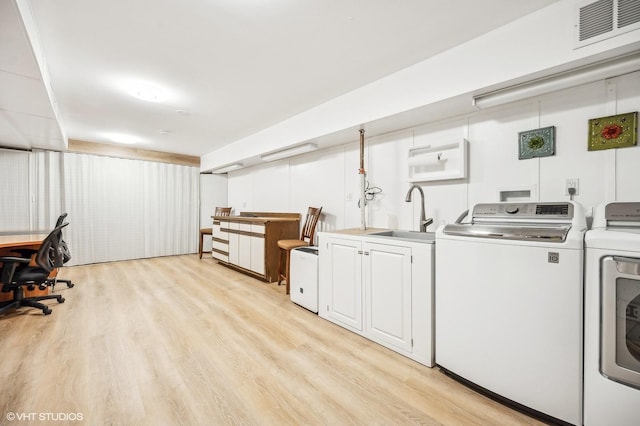 clothes washing area featuring sink, light hardwood / wood-style flooring, cabinets, and independent washer and dryer