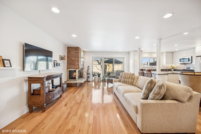 living room featuring a fireplace, decorative columns, and light hardwood / wood-style flooring