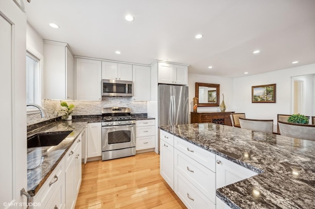 kitchen with white cabinetry, appliances with stainless steel finishes, sink, and light hardwood / wood-style flooring