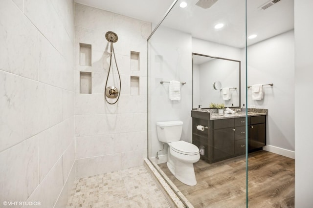 bathroom featuring vanity, wood-type flooring, toilet, and tiled shower