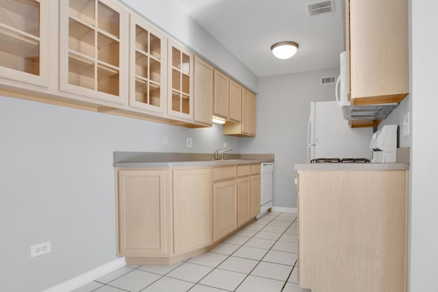 kitchen featuring sink, white appliances, light brown cabinetry, and light tile patterned flooring