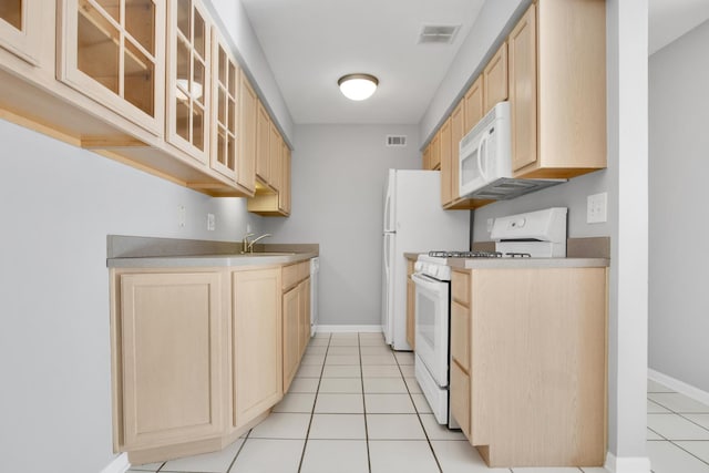 kitchen featuring sink, light tile patterned flooring, white appliances, and light brown cabinetry